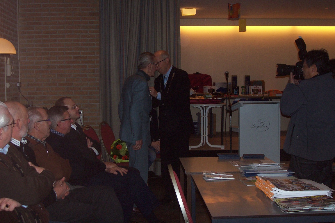 Izak op't Hof ontvangt de bijbehorende versierselen uit handen van burgemeester van der Zaag van de gemeente Goes.